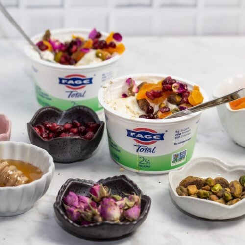 ¾ view of yogurt cups with an array of Persian toppings for making jeweled yogurt parfaits.