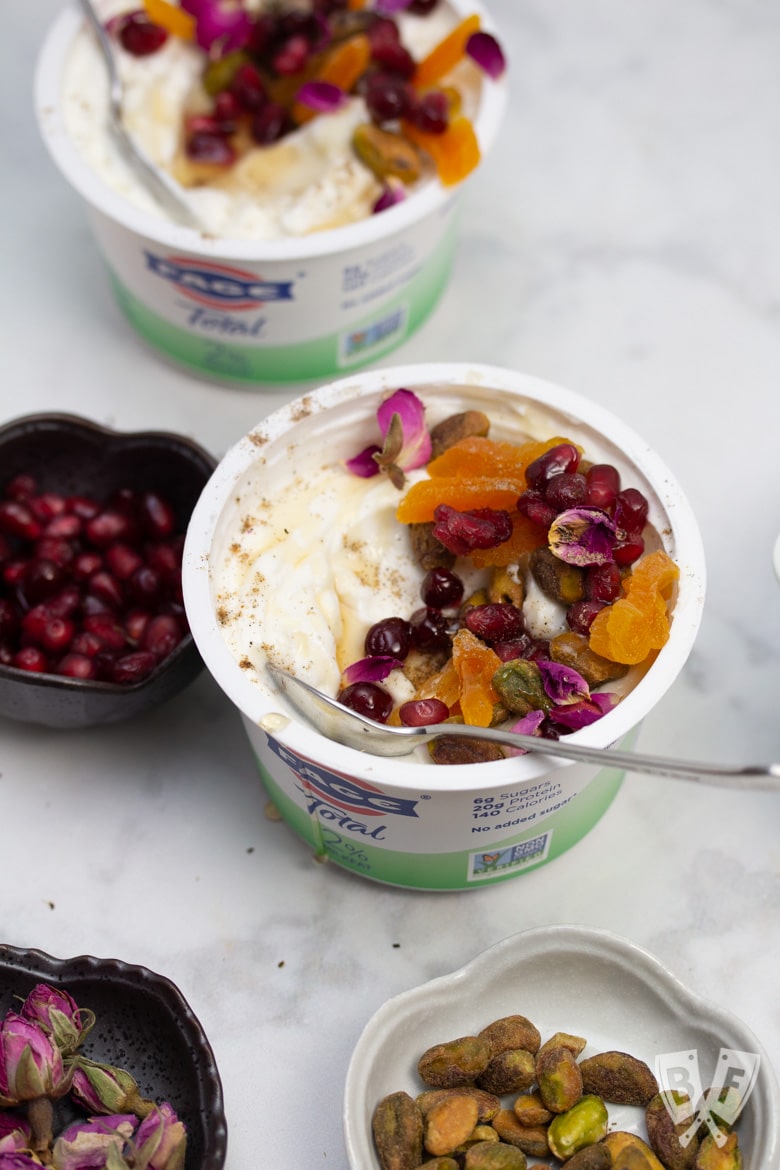 Overhead view of yogurt cups with an array of Persian toppings for making jeweled yogurt parfaits.