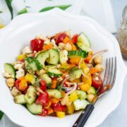 Overhead view of a bowl of Mediterranean Chickpea Salad with Lemon-Herb Vinaigrette with dressing on the side