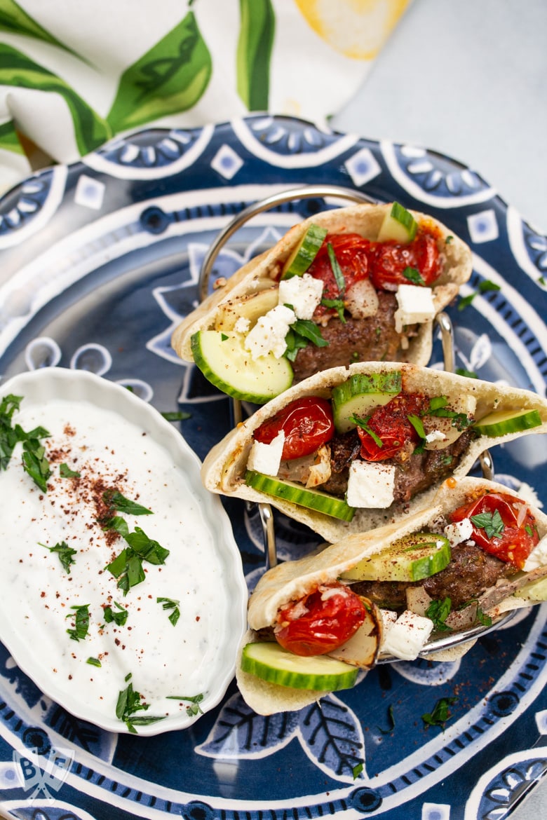 Overhead view of Broiler Kebab served in pita bread with a side of mast-o-khiar yogurt sauce.