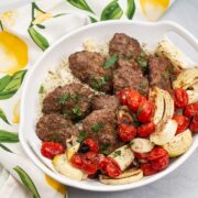 Overhead view of a platter of kebab with onions and tomatoes.