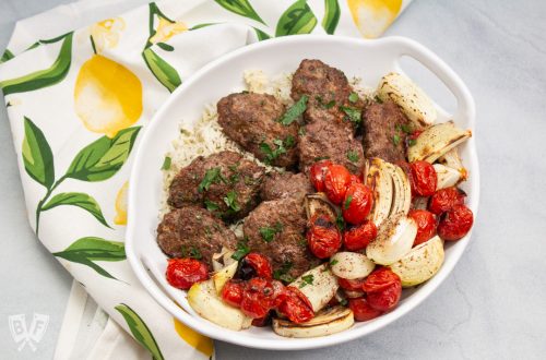 Overhead view of a platter of kebab with onions and tomatoes.