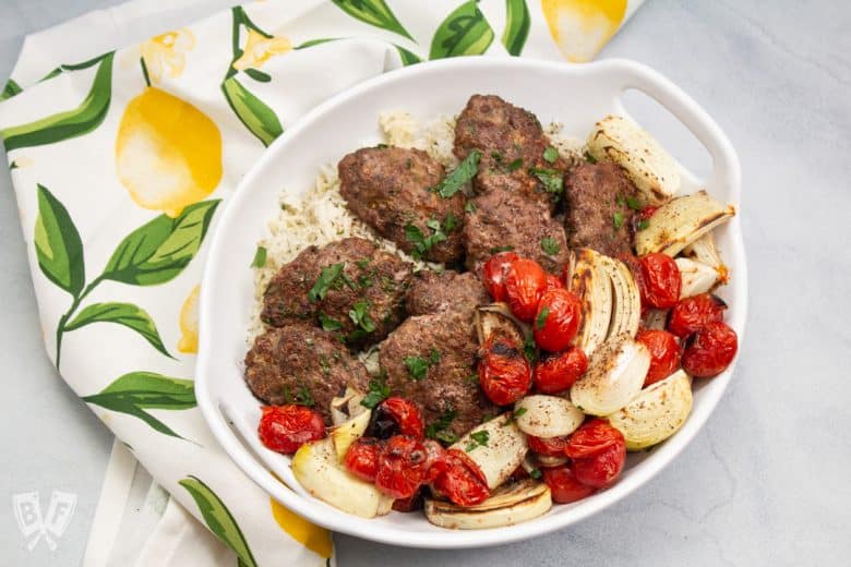 Overhead view of a platter of kebab with onions and tomatoes.