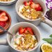 Overhead view of Greek yogurt parfaits with colorful tropical fruit toppings.