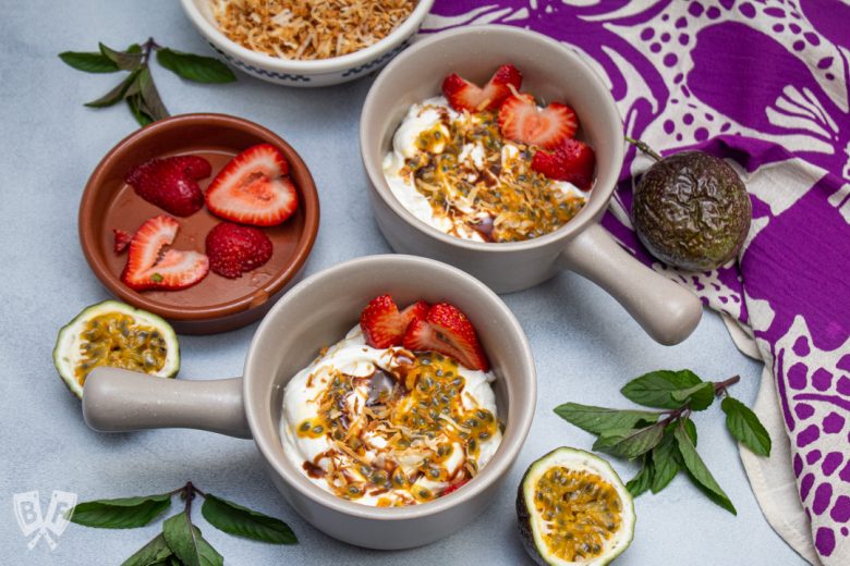 Overhead view of Greek yogurt parfaits with colorful tropical fruit toppings.