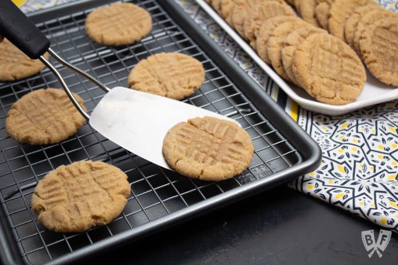 Spatula removing a peanut butter cookie from a baking sheet