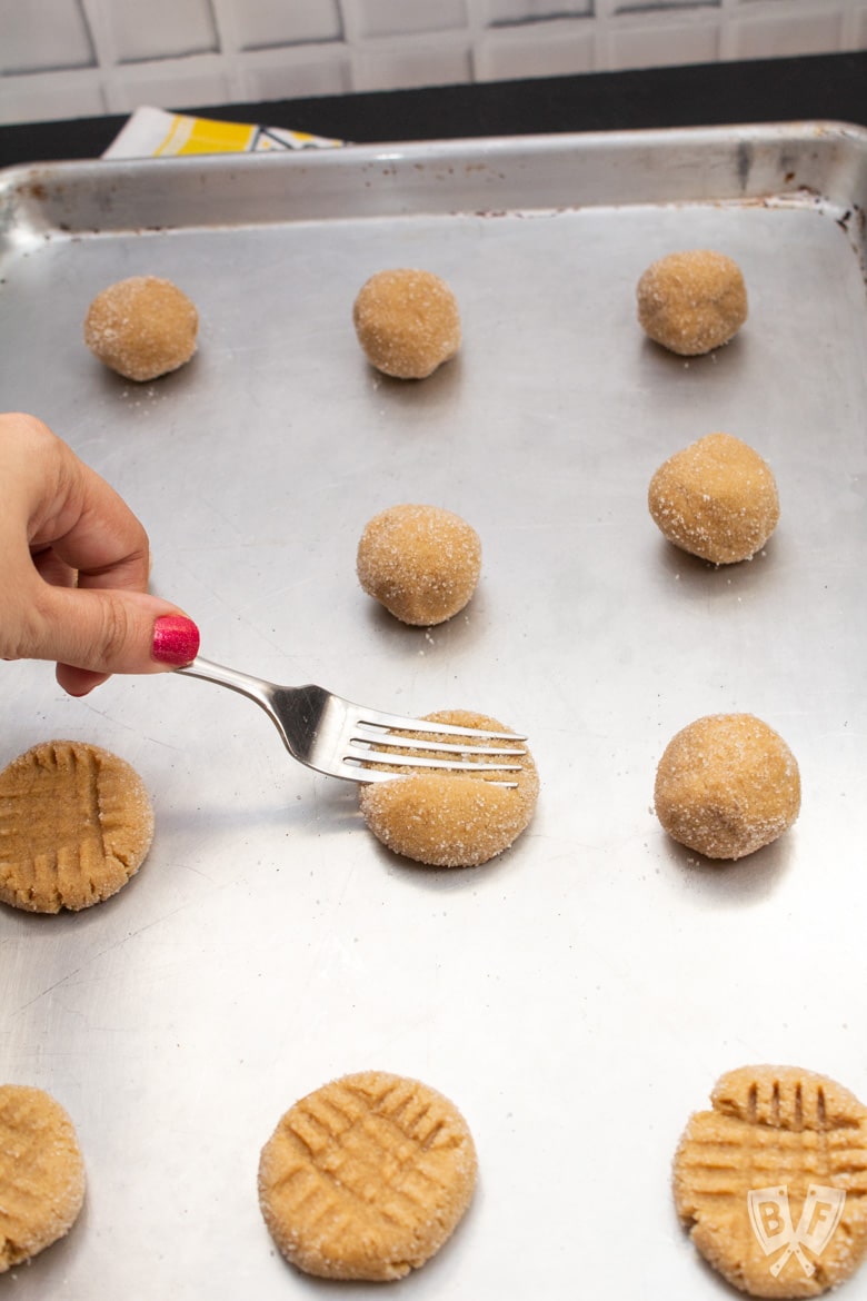 Pressing the tines of a fork into peanut butter cookie dough.
