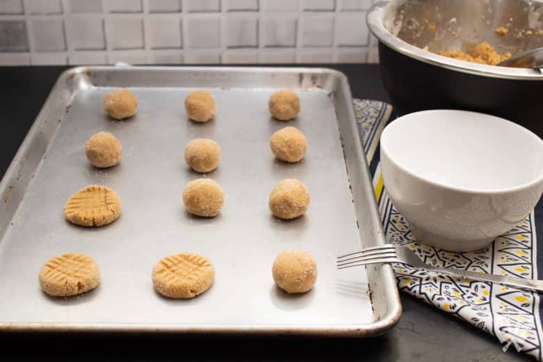 Peanut butter cookie dough balls lined up on a baking sheet