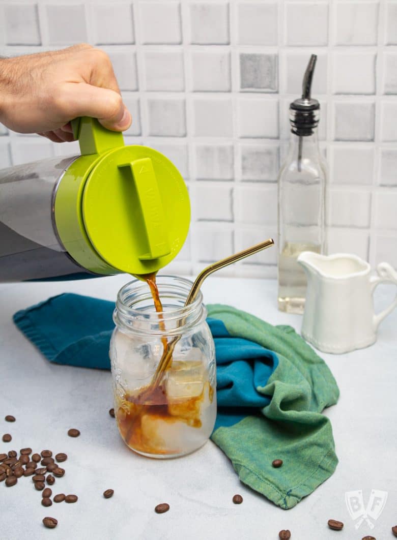 Pouring cold brew coffee into a glass of ice water