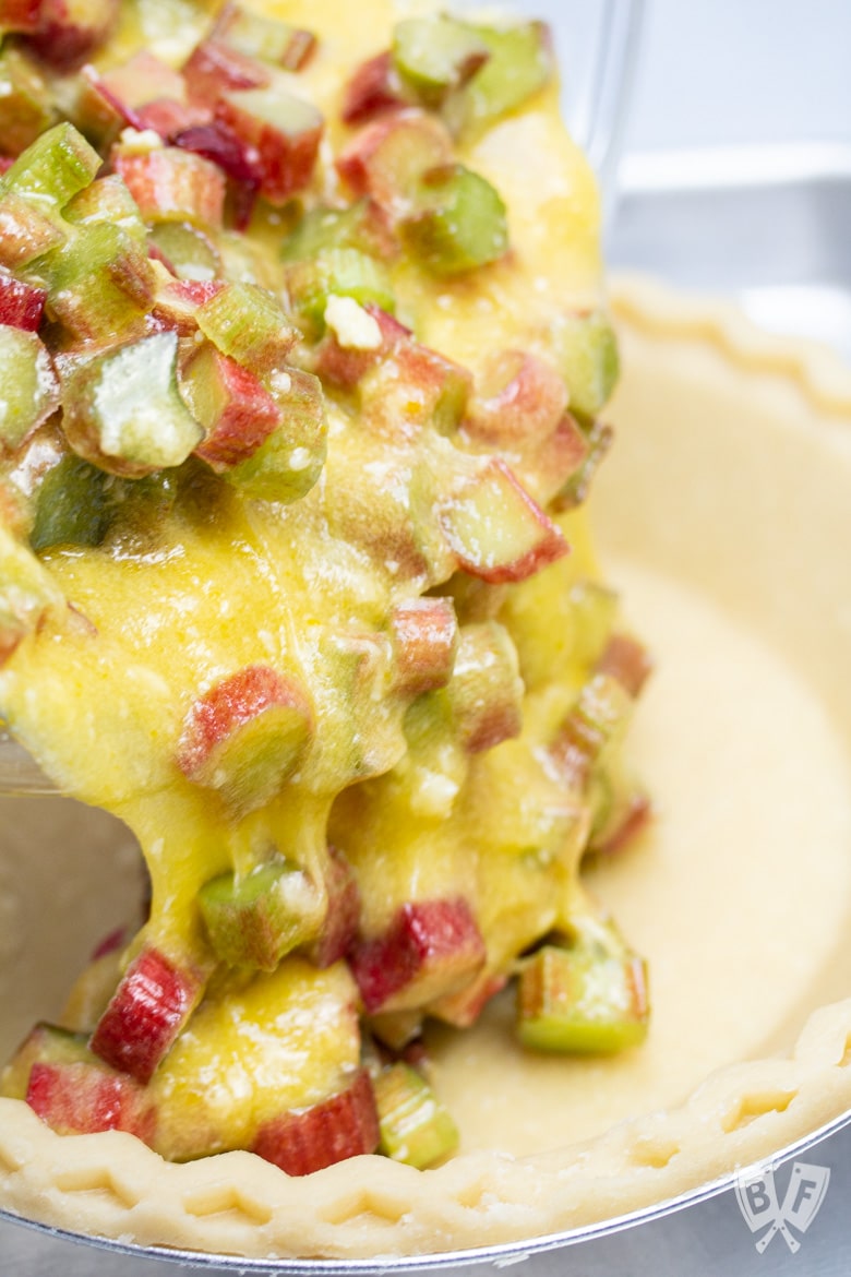 Rhubarb custard filling being poured into a pie crust.