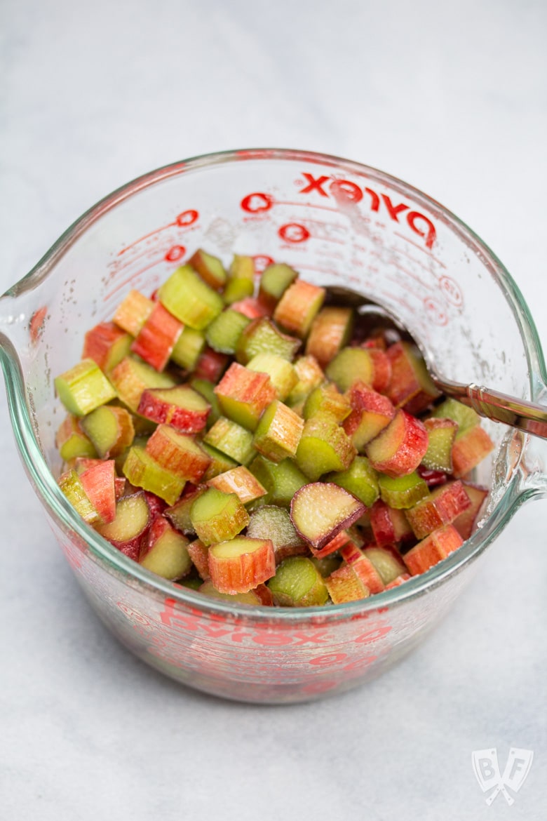 Overhead view of a bowl of sliced rhubarb mixed with sugar.