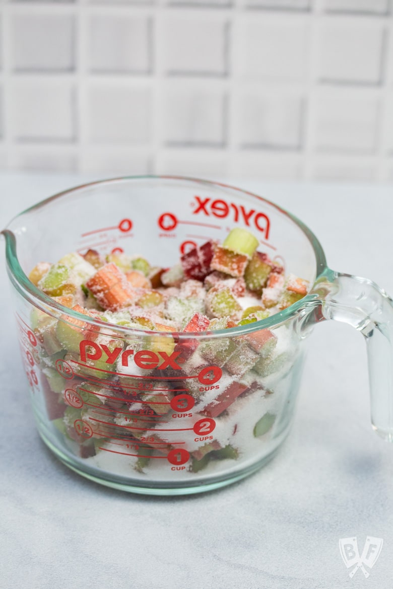 Overhead view of a bowl of sliced rhubarb mixed with sugar.