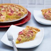 A rhubarb custard pie with plated slices and forks