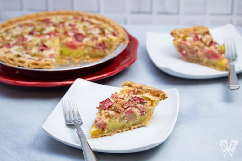 A rhubarb custard pie with plated slices and forks