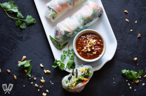 Platter of Vietnamese fresh spring rolls with shrimp & peanut sauce surrounded by ingredients.
