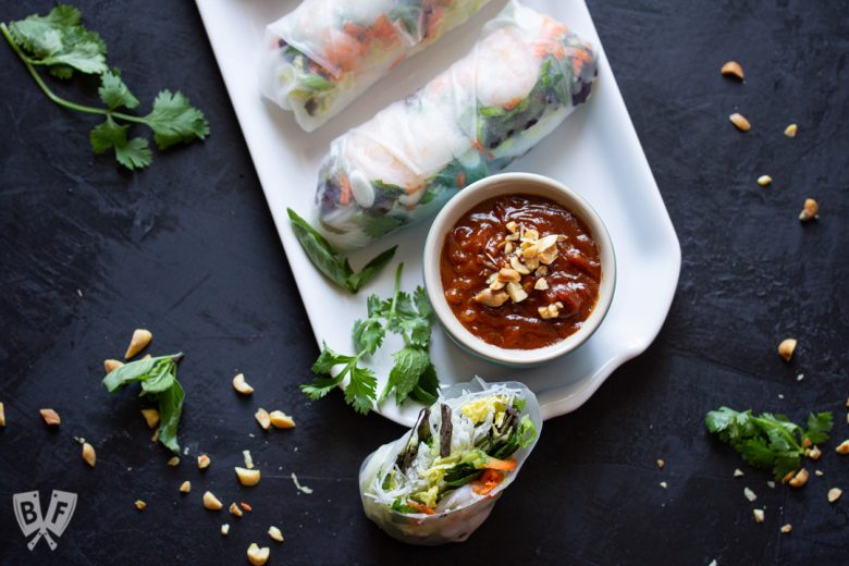 Platter of Vietnamese fresh spring rolls with shrimp & peanut sauce surrounded by ingredients.