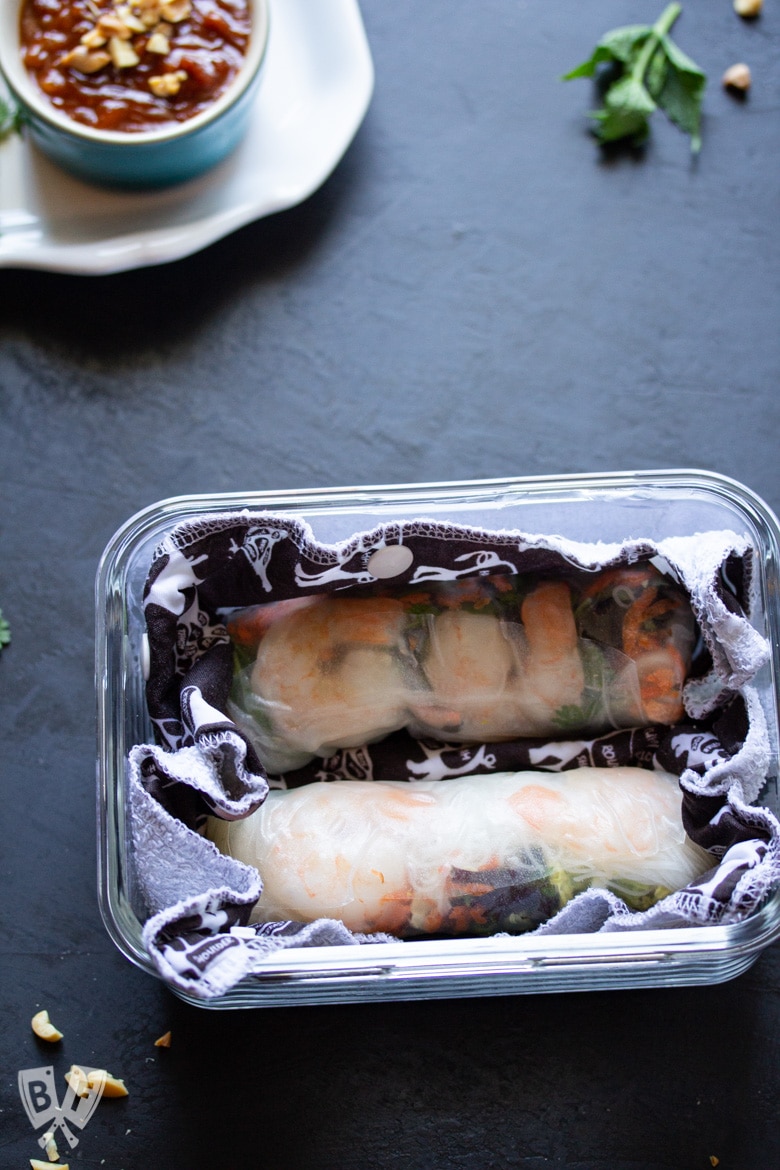 Fresh spring rolls packed into a glass storage container.