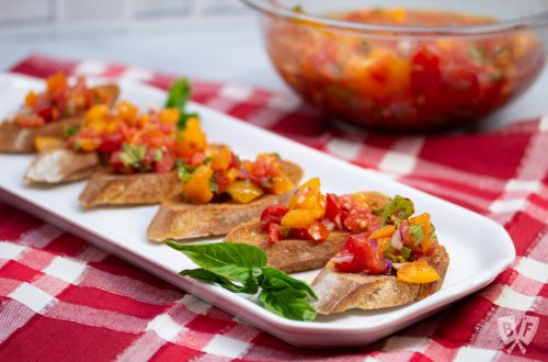Platter of Italian Bruschetta with bowl of tomato mixture in the background