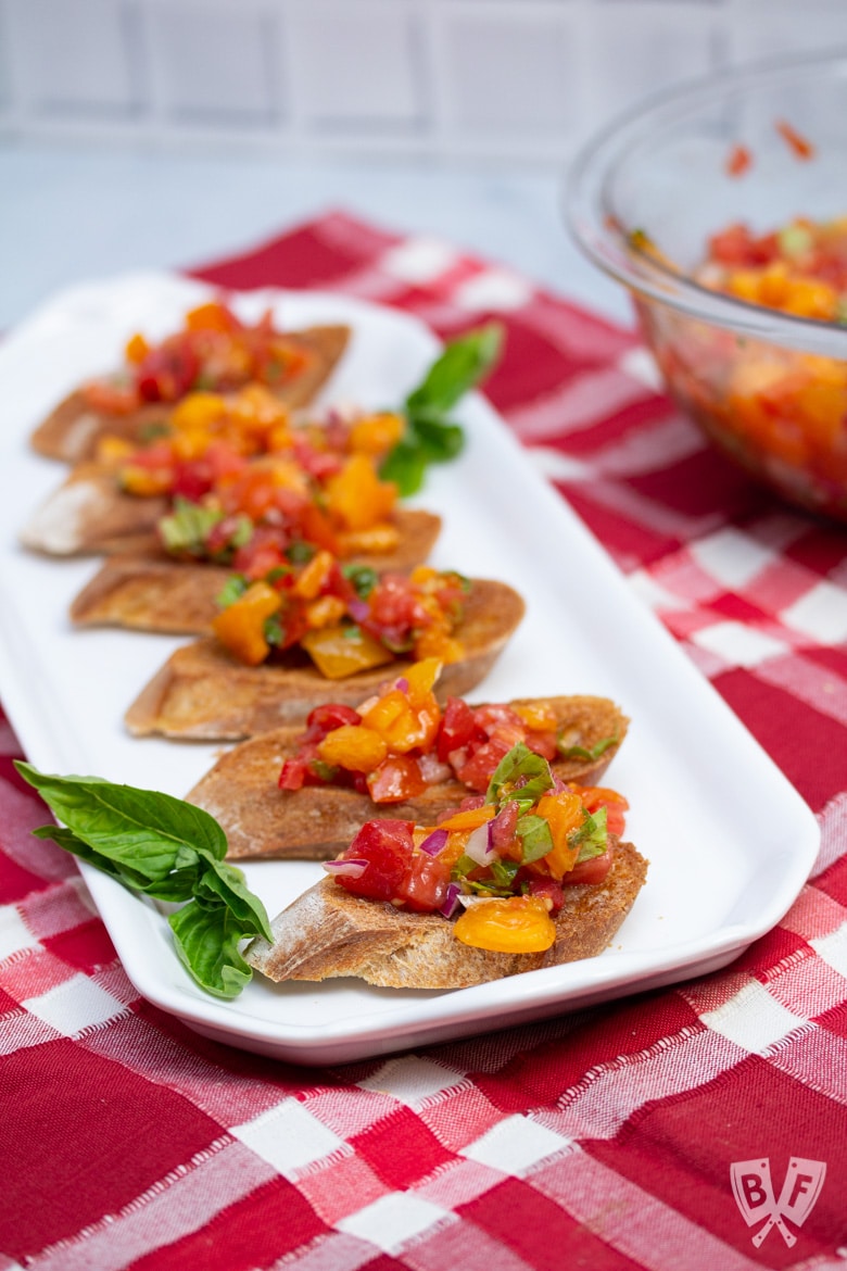 Platter of bruschetta with a bowl of the tomato mixture to the side.