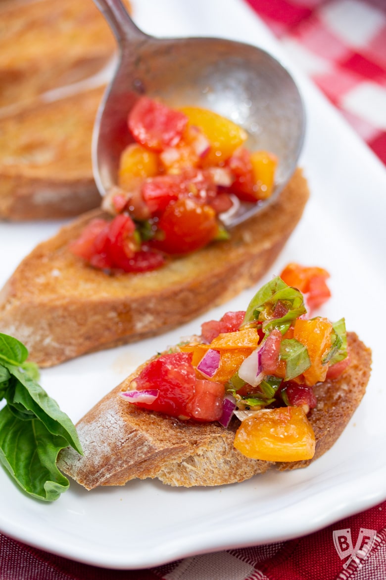 Spooning tomato bruschetta mixture onto crostini.