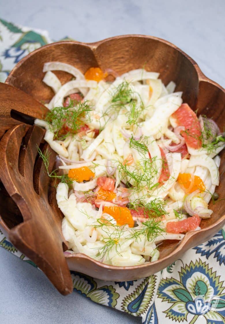 Bowl of fennel citrus salad with salad hand tools to the side.