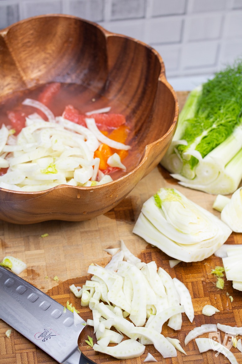 Chopping a bulb of fennel to add to a bowl of fennel and citrus salad.