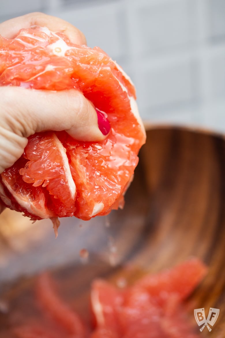 Squeezing juice from the membranes of a grapefruit.