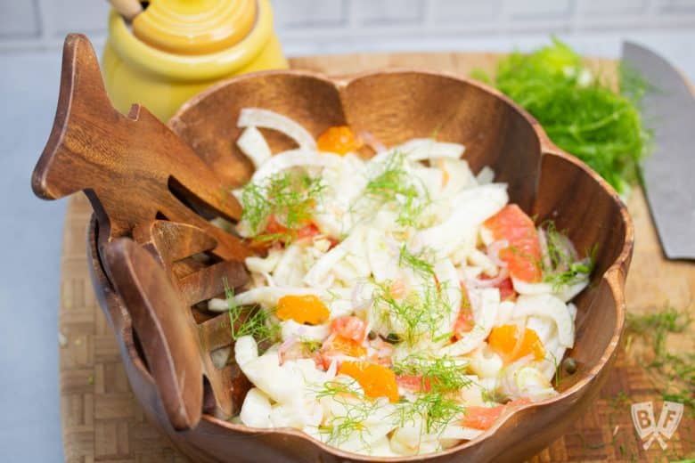 Bowl of fennel citrus salad with knife and honey pot alongside.