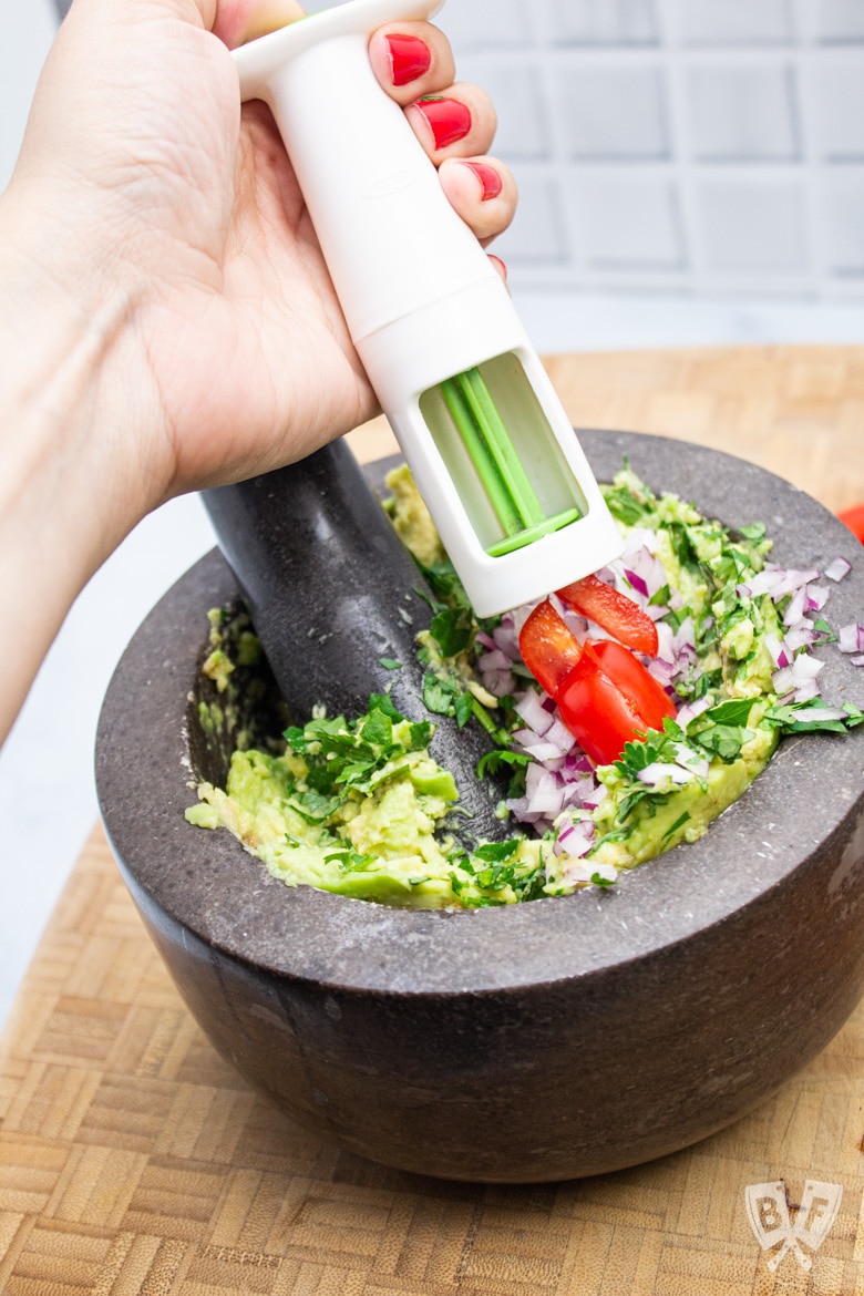 Using a tool to quickly quarter tomatoes for guacamole.