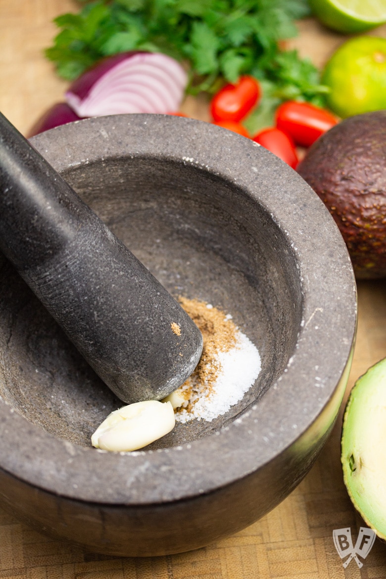 Smashing garlic and spices with a mortar and pestle for restaurant-style guacamole.