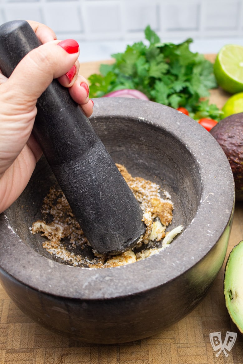 Smashing garlic and spices with a mortar and pestle.