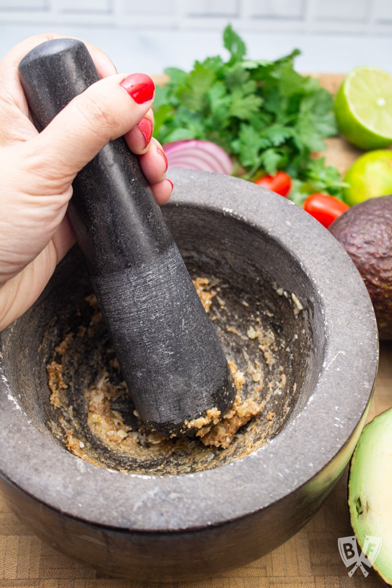 Making a paste from garlic and spices for homemade guacamole.