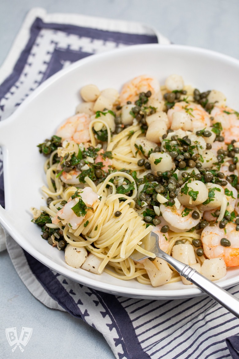 Fork twirling pasta in a bowl of Shrimp + Scallop Linguine with Lemon Caper Butter