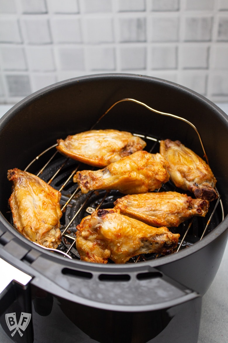 Air fryer tray with cooked chicken wings on the rack