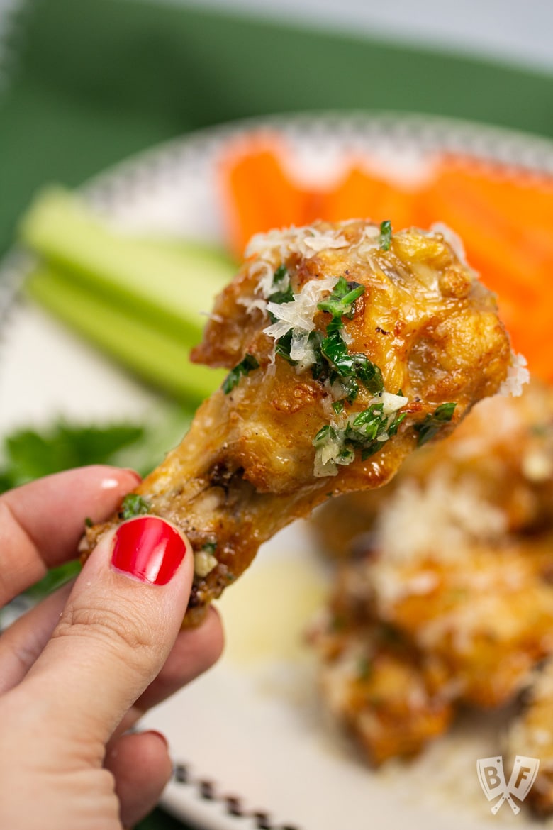 Hand holding a garlic parmesan chicken wing