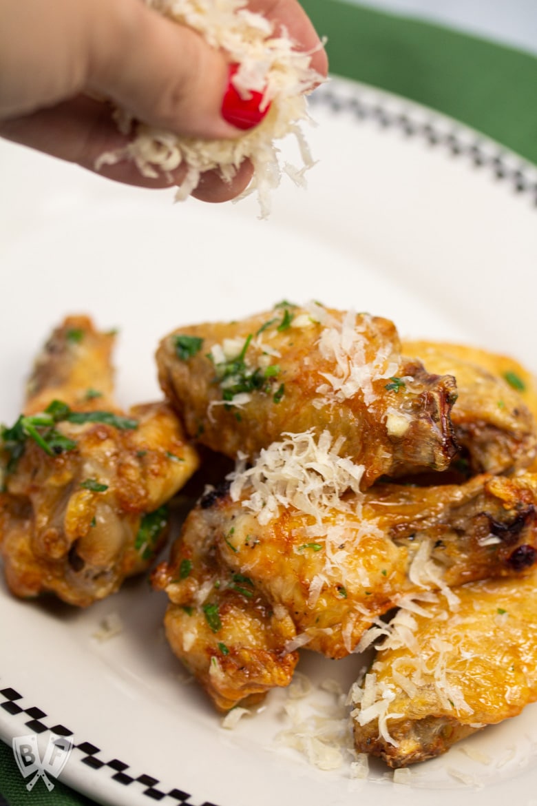 Sprinkling Parmesan cheese on air-fried chicken wings