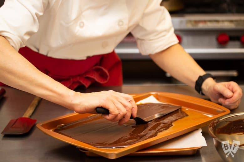 spreading chocolate onto caramel for homemade toffee