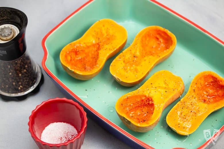 Baking dish with 4 honeynut squash halves ready to roast