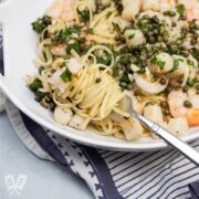Fork twirling pasta in a bowl of Shrimp + Scallop Linguine with Lemon Caper Butter