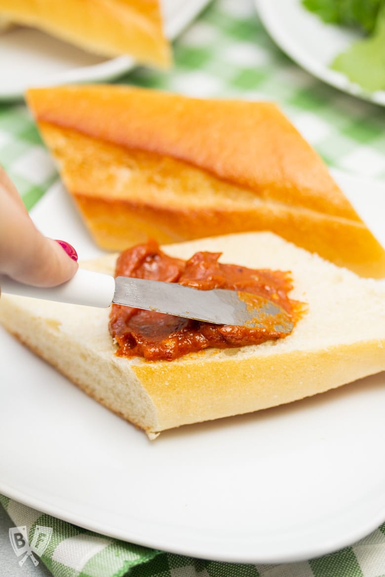 Spreading peanut sauce onto a sliced baguette