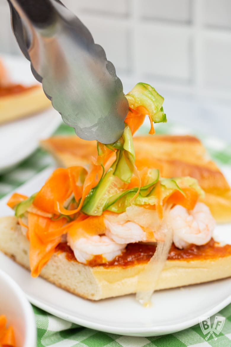 Adding pickled vegetables to a Vietnamese shrimp sandwich