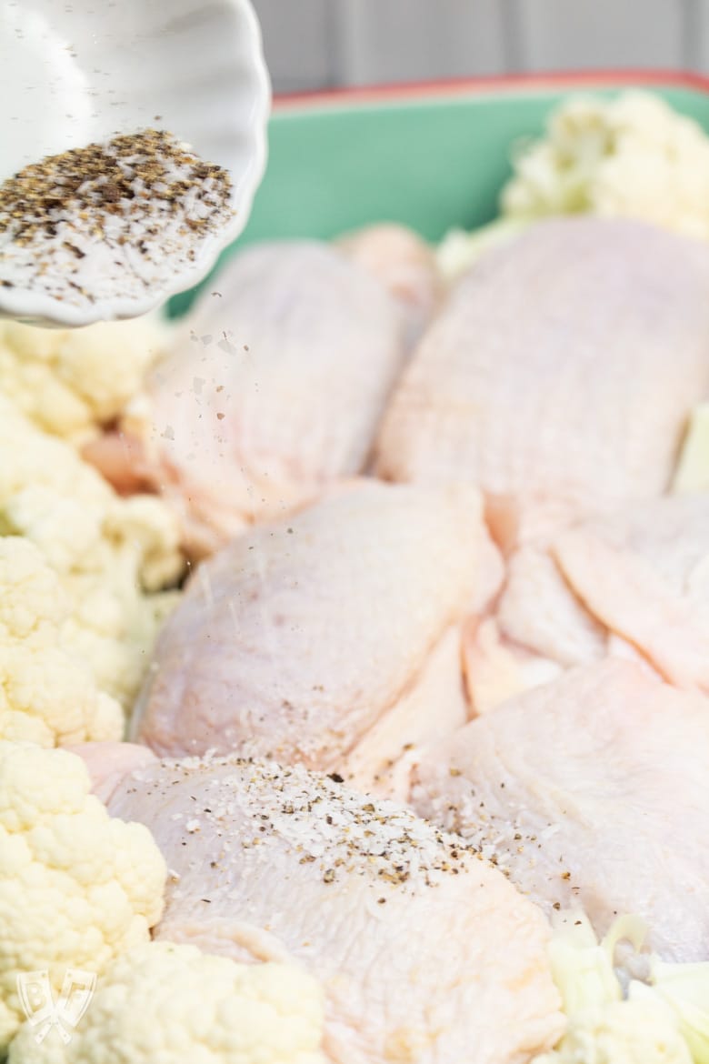 Chicken thighs being seasoned with salt and pepper