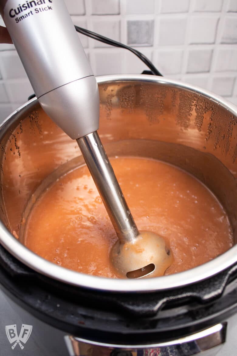 An immersion blender pureeing homemade applesauce in an Instant Pot.