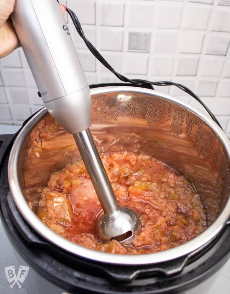 Immersion blender ready to puree homeade applesauce in an Instant Pot.