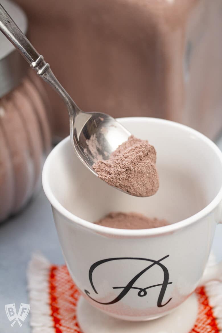 Spooning homemade hot cocoa mix into a mug.