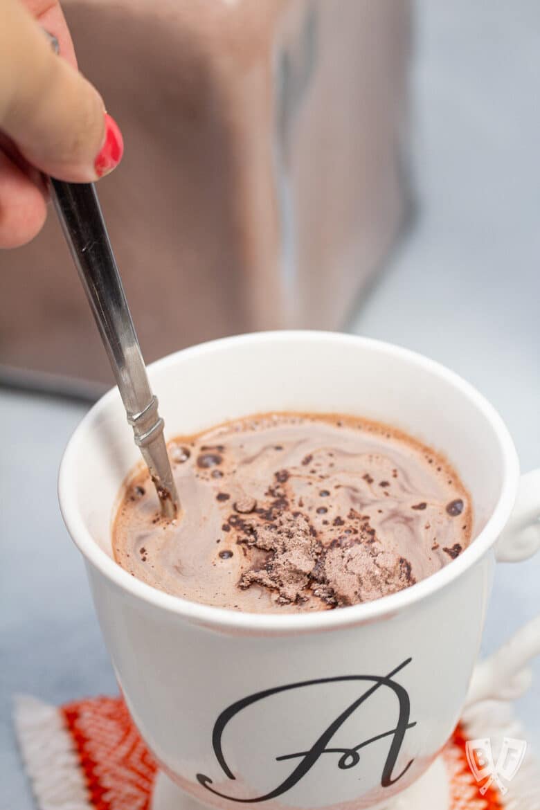 Stirring homemade hot cocoa mix into a mug of hot water.