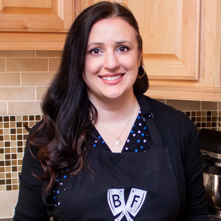 Ashley Covelli standing in the kitchen wearing an apron with the Big Flavors logo.