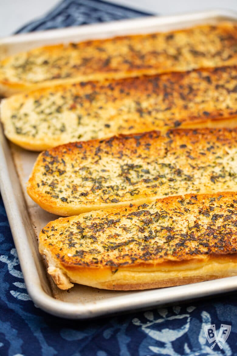 Baking sheet with 4 big pieces of golden brown garlic bread.