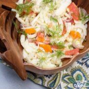 Bowl of fennel citrus salad with salad hand tools to the side.