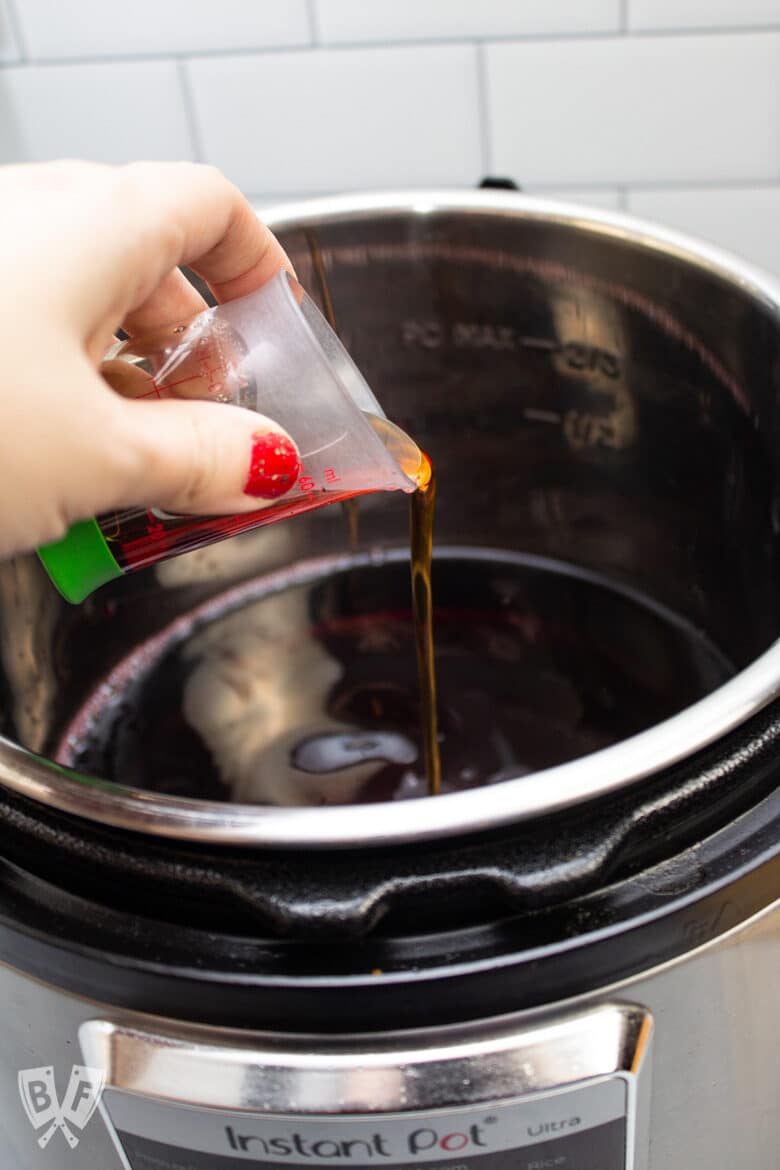 Pouring brandy into an Instant Pot with red wine.